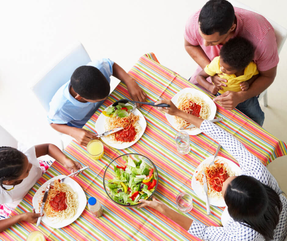 A family gathered around a table, enjoying a meal together with various dishes and drinks in front of them.