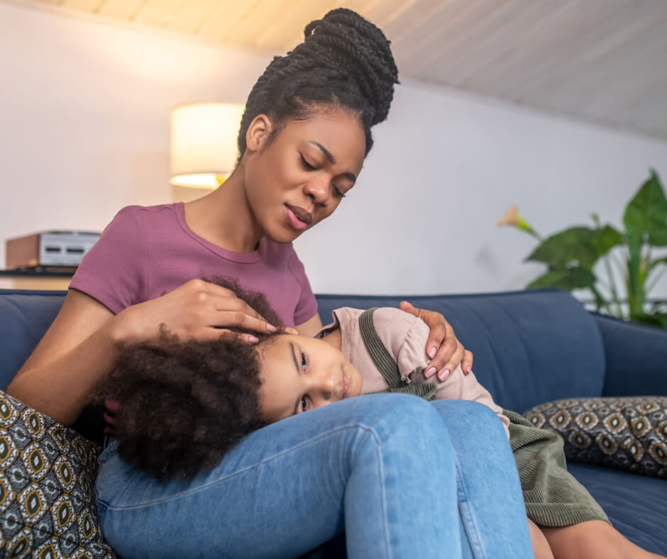 A woman and her child sit together on a cozy couch, sharing a moment of relaxation and connection