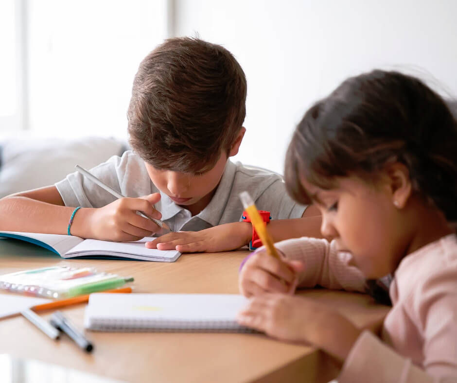 Two kids doing homework together at a table, building an after-school routine to improve focus and concentration