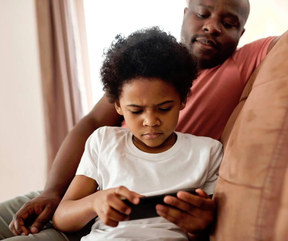 Child using smartphone on couch with parent, illustrating dopamine screen addiction and low boredom tolerance in kids