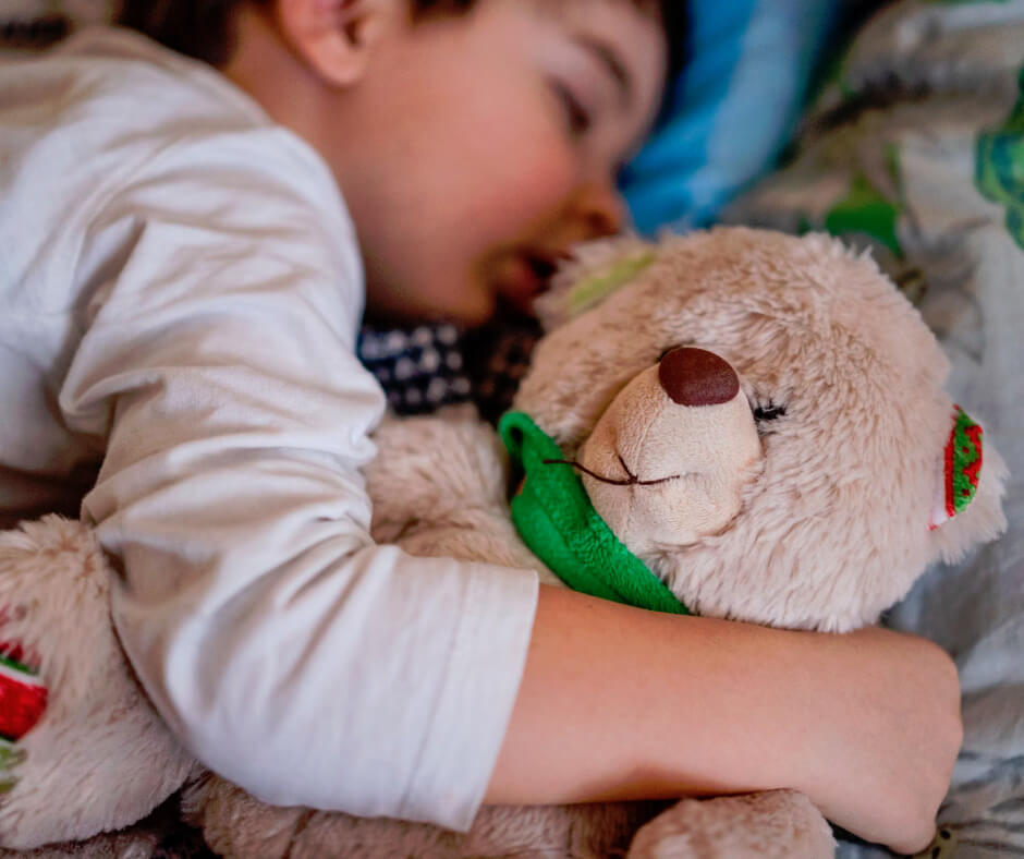 Young child sleeping peacefully hugging teddy bear, illustrating healthy sleep habits for cognitive development in kids